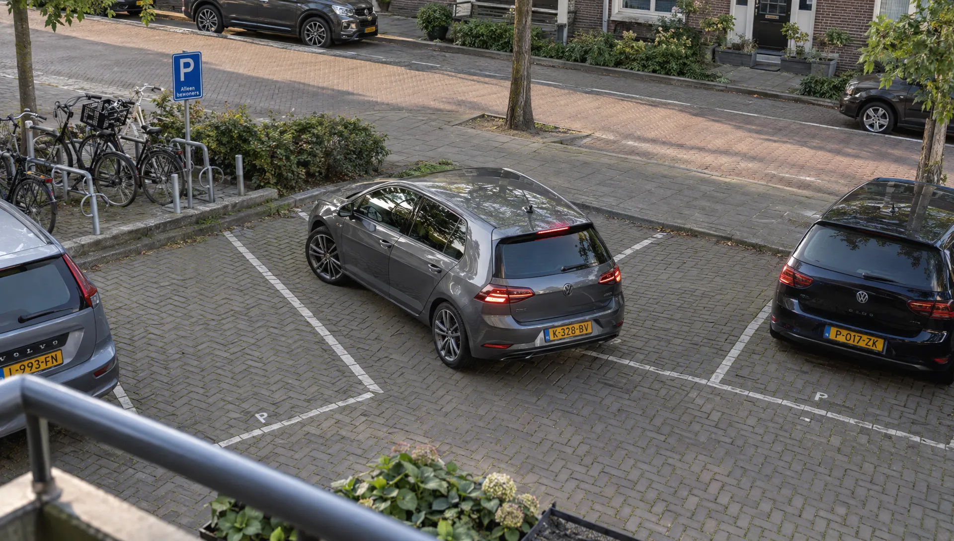 Een auto met 18-inch velgen parkeert in een stedelijke straat, met de wielen zichtbaar naast de belijnde parkeerplaats.