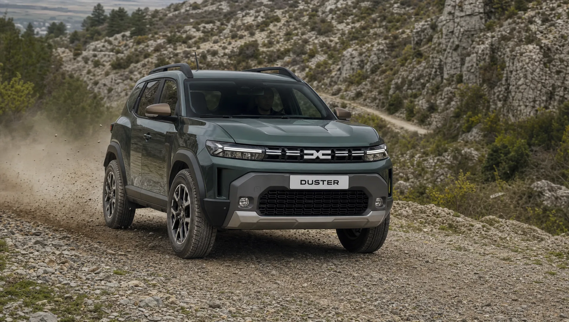 Een Dacia Duster rijdt over een gravelpad met robuuste velgen en duidelijke bandwang voor licht terrein.