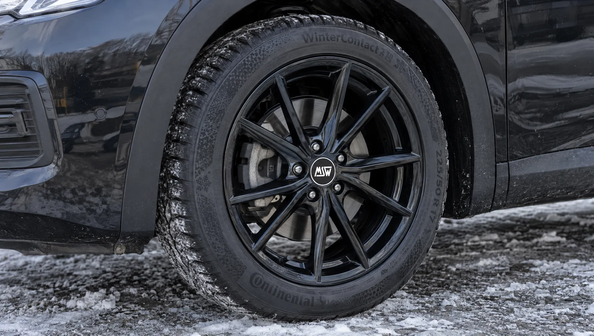 Een donker gelakte MSW-velg met winterband is gemonteerd op een auto; de spaken, bandwang en ruimte rond de remklauw zijn goed zichtbaar.